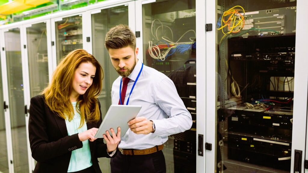 Technicians using digital tablet while analyzing server